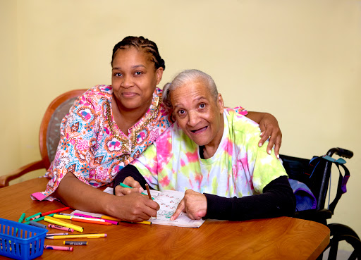 A joyful moment shared between a caregiver and an elderly person as they engage in an art activity together.