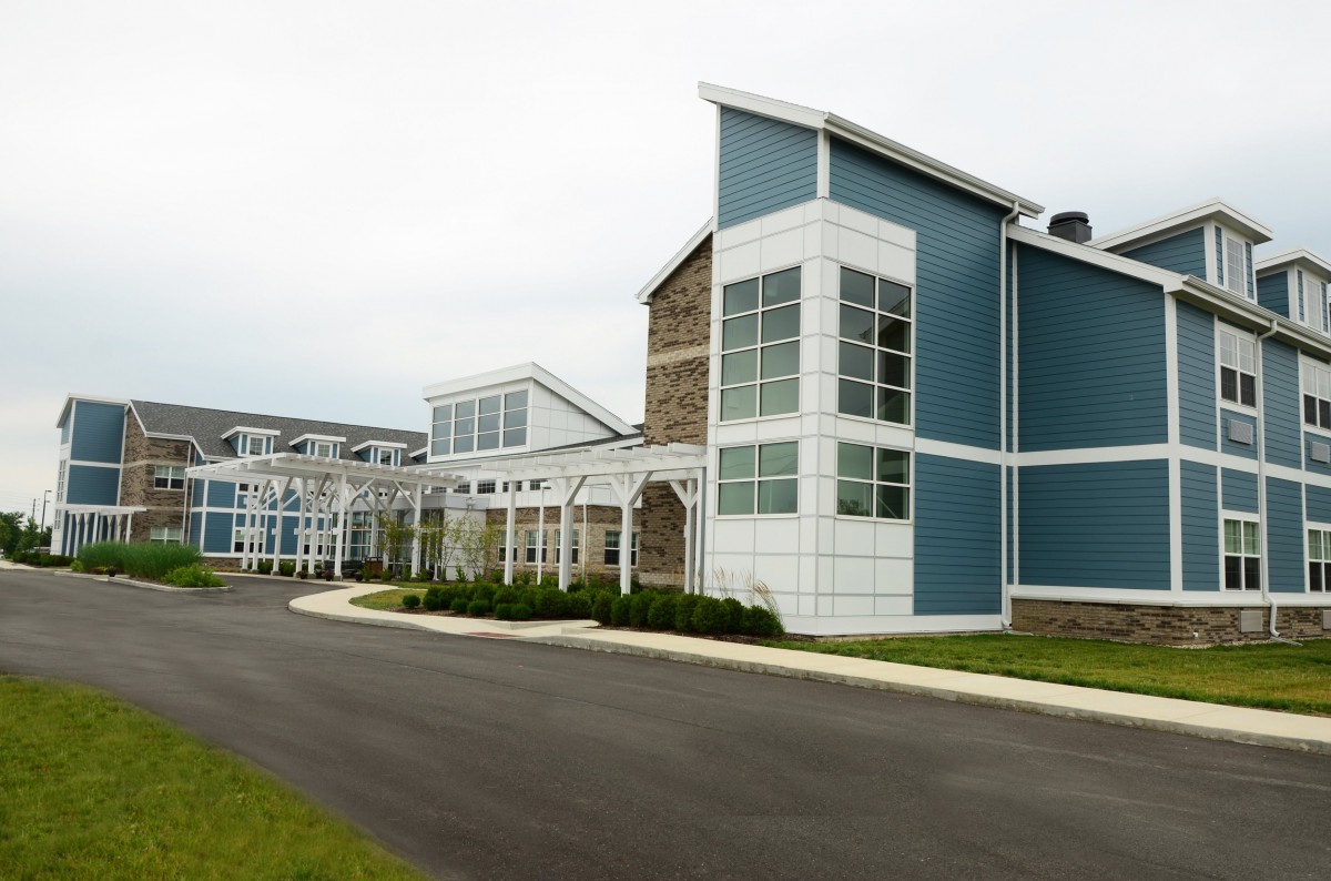 A modern building with a sleek design featuring large glass windows and a paved entrance.