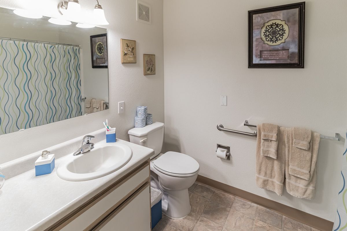 A clean and organized bathroom with a sink, toilet, and shower curtain.