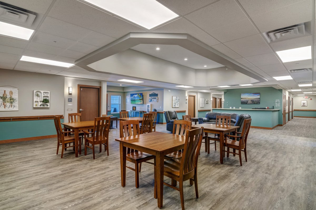 A modern dining area with wooden tables and chairs, featuring contemporary lighting and decor.