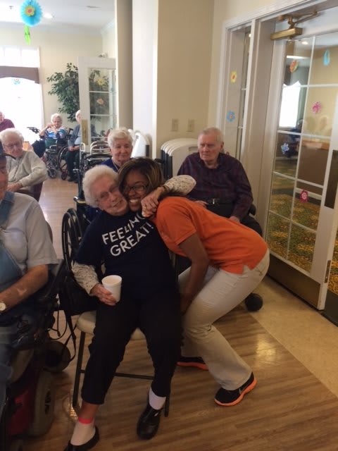 A joyful moment shared between an elderly resident and a caregiver in a nursing home setting.