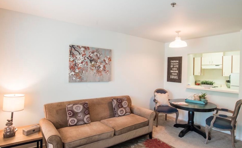 A cozy living room with a brown sofa, decorative cushions, and wall art.