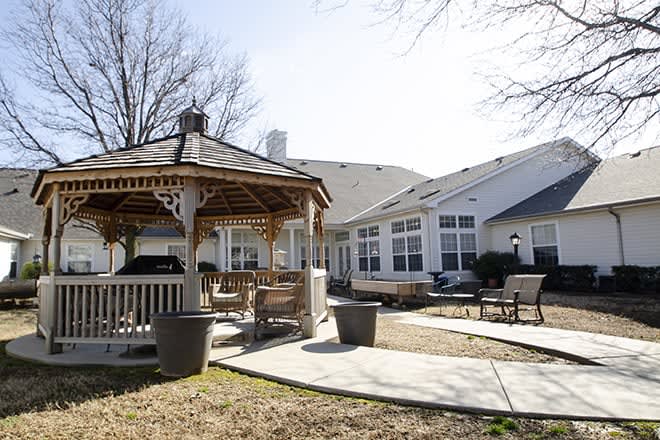 A backyard with a gazebo and patio seating in a sunny residential area.