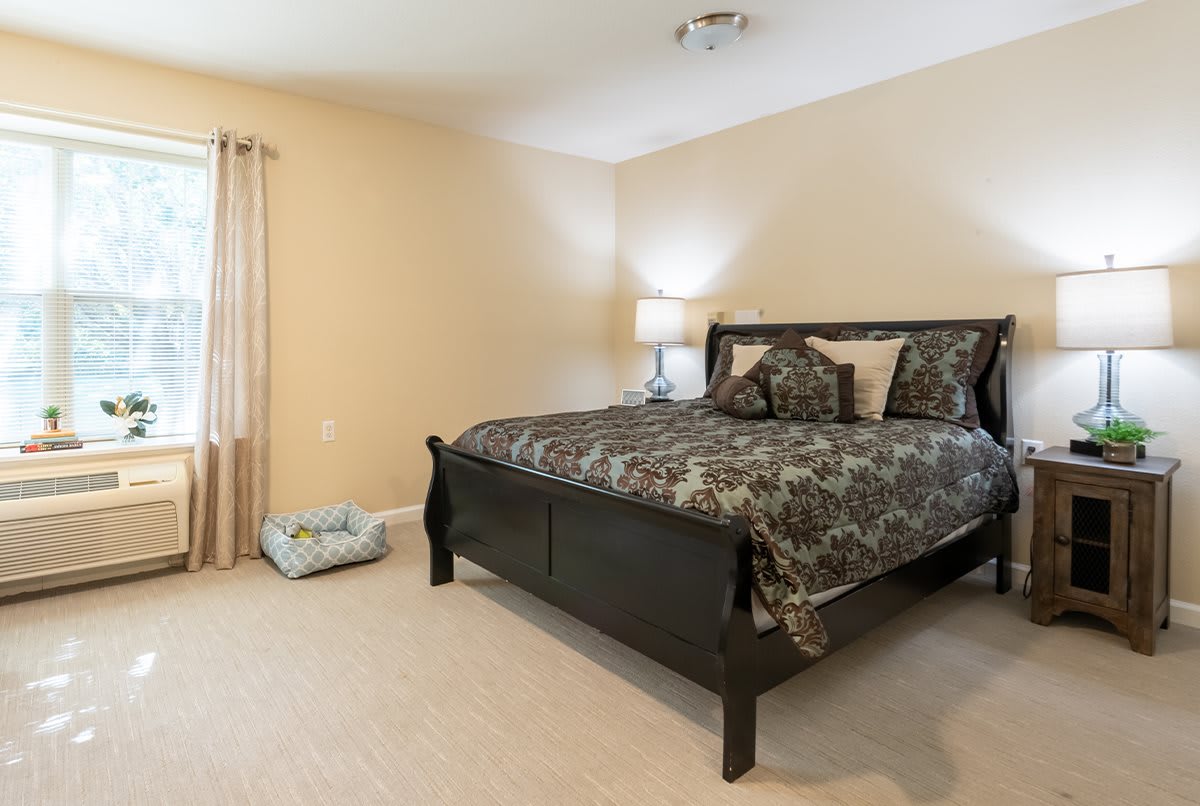 A cozy bedroom with a large bed, decorative pillows, and a bedside lamp.