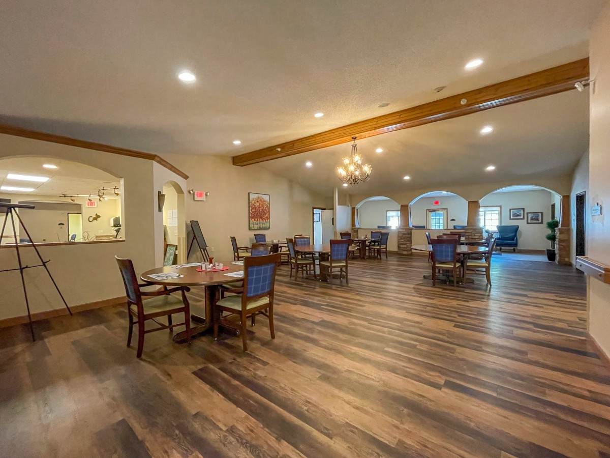 A spacious and elegant dining room with wooden floors and neatly arranged tables and chairs.