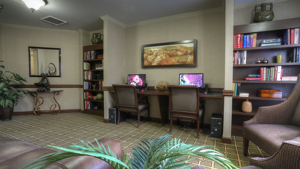 A cozy office space featuring two computer workstations and a bookshelf.