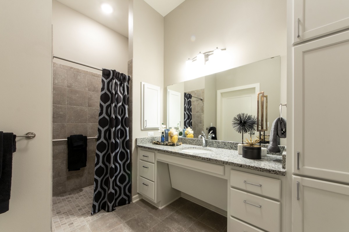 A modern bathroom featuring a large mirror, a double sink vanity, and a stylish shower curtain.