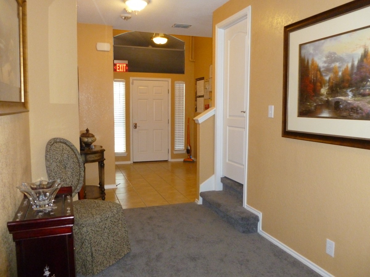 A cozy hallway featuring a staircase, seating area, and wall art.