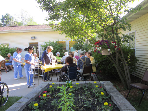 A lively outdoor community event with seniors engaging in activities near a garden.