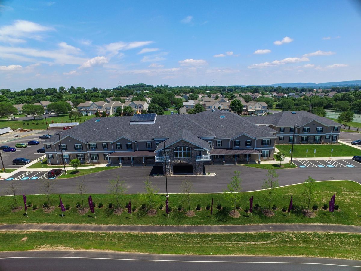 Aerial view of a commercial building with surrounding parking lot and landscape.