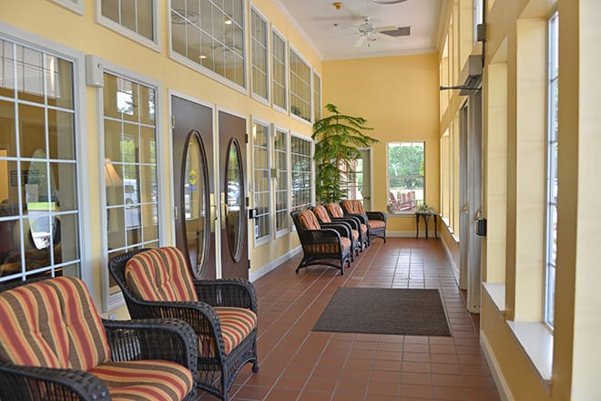 A cozy waiting area with wicker chairs and large windows.