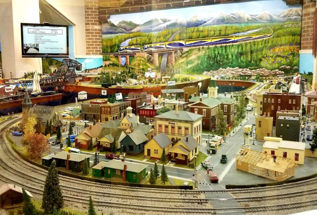 A detailed model train setup depicting a miniature town with tracks, buildings, and landscape scenery.