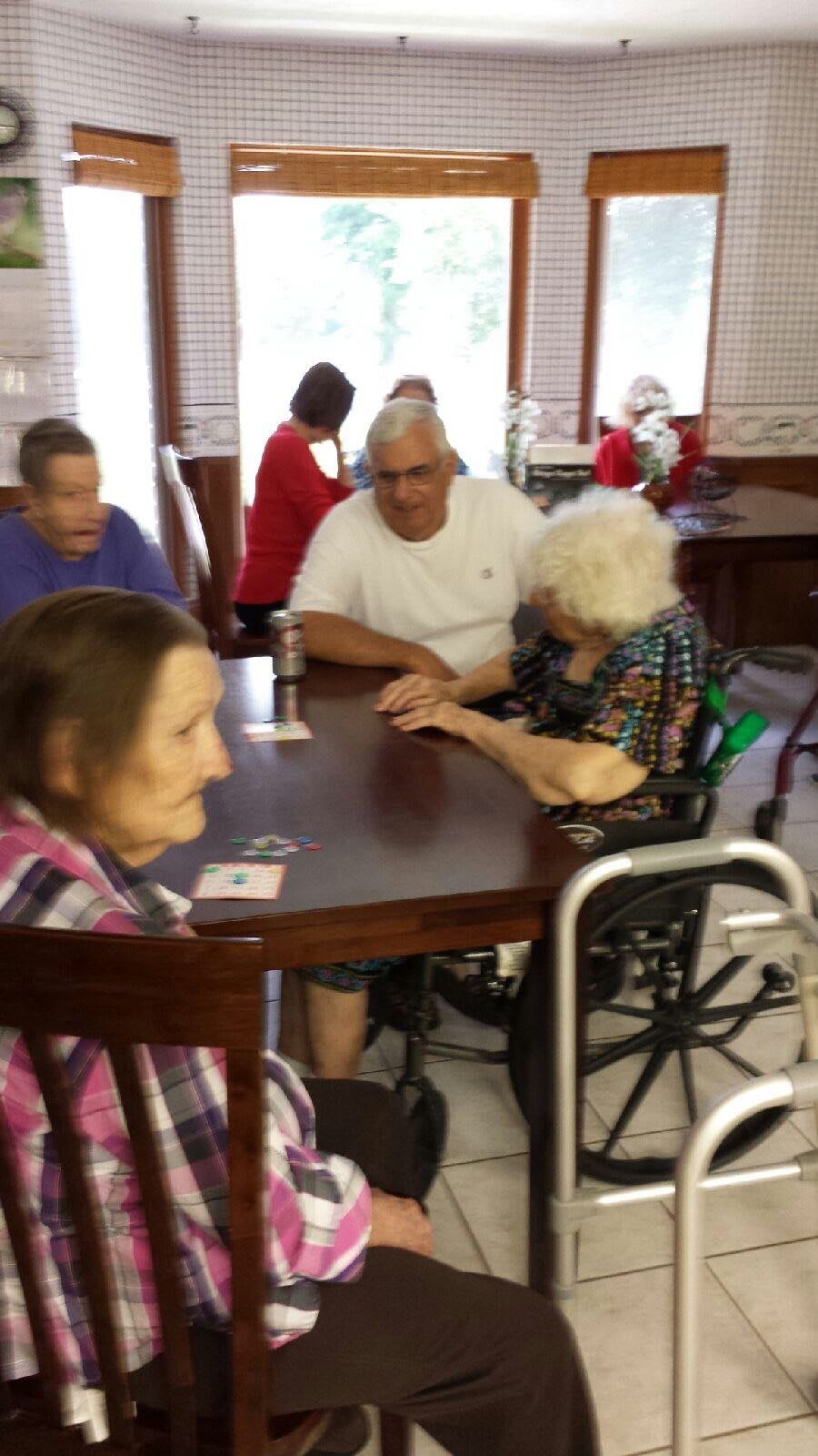 A group of seniors gathered around a table in a care facility.