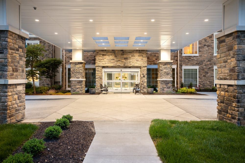 A modern building entrance with stone walls and a covered driveway.