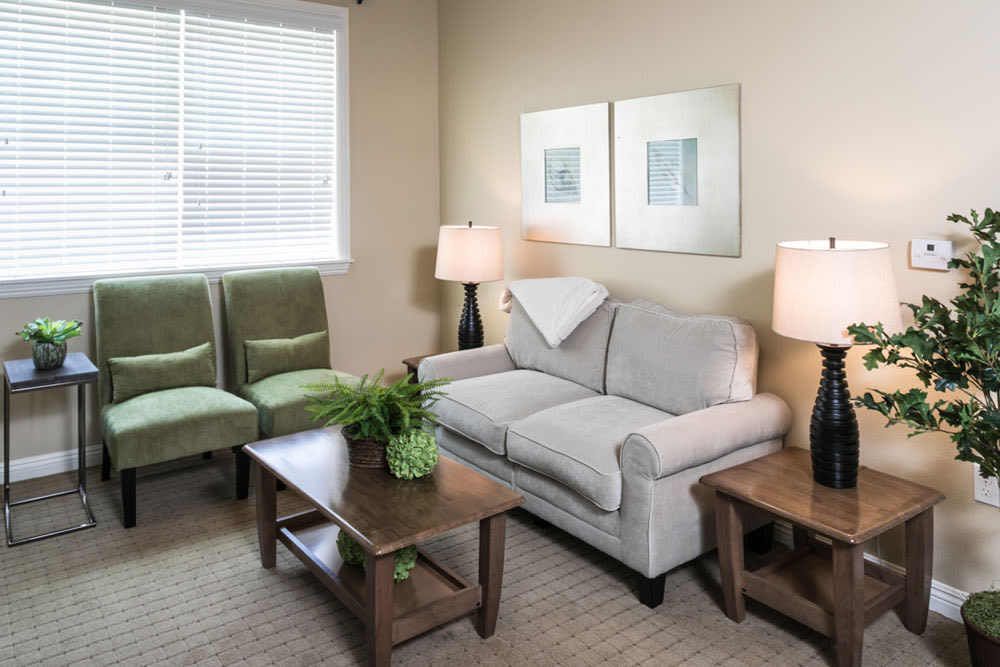 A cozy living room with a sofa, chairs, and coffee tables under soft lighting.