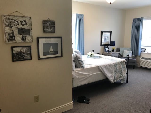 A cozy bedroom featuring a neatly made bed, wall art, and comfortable seating.