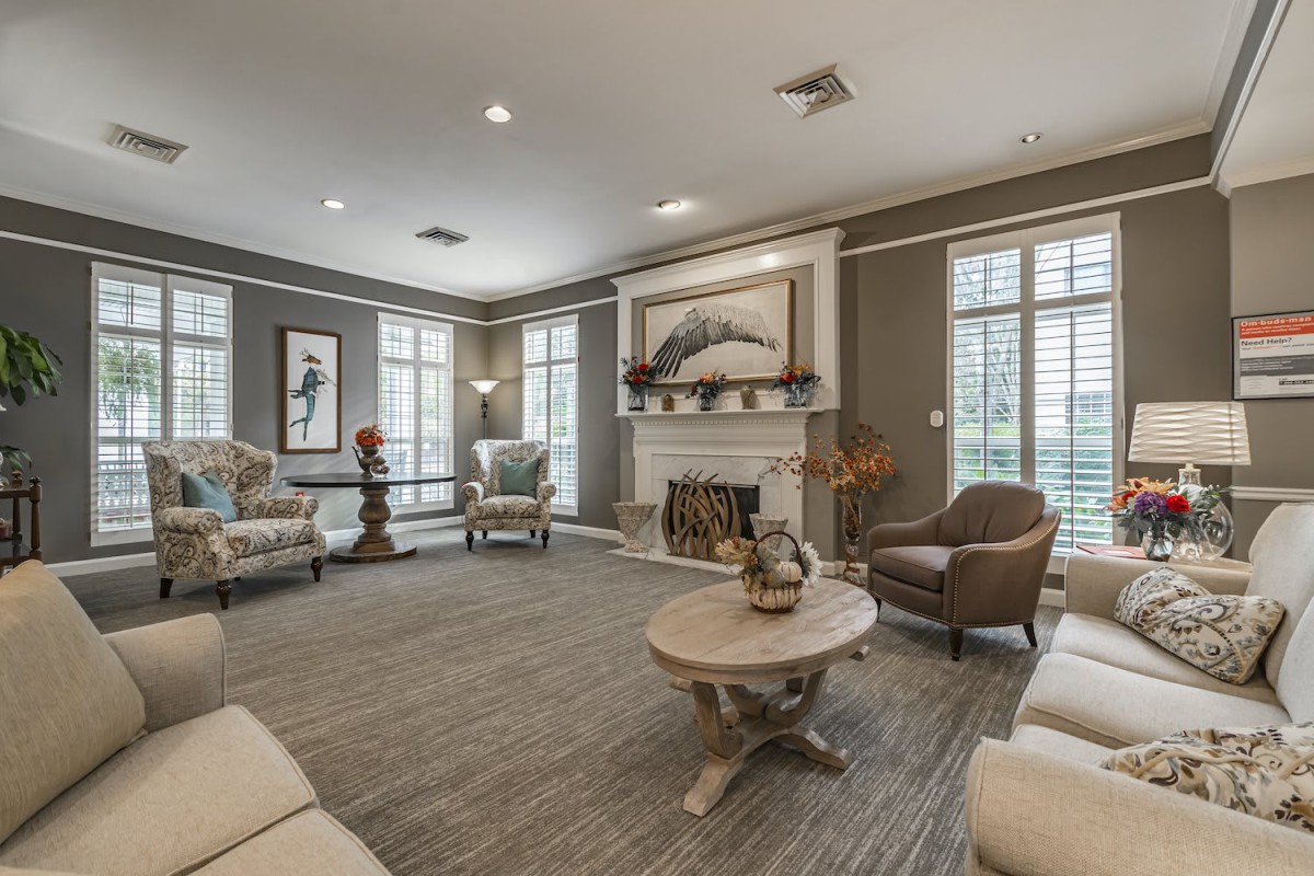 A spacious living room featuring comfortable seating, a central coffee table, and a fireplace adorned with art pieces.
