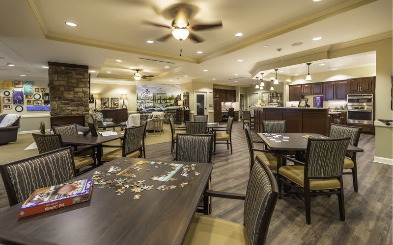 A cozy dining area with tables, chairs, and a puzzle in progress on one table.
