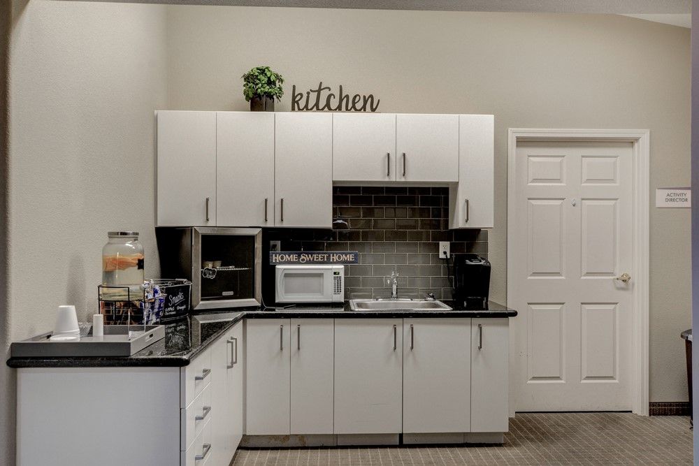 Modern kitchen setup with white cabinets, a microwave, and a coffee maker on the countertop.