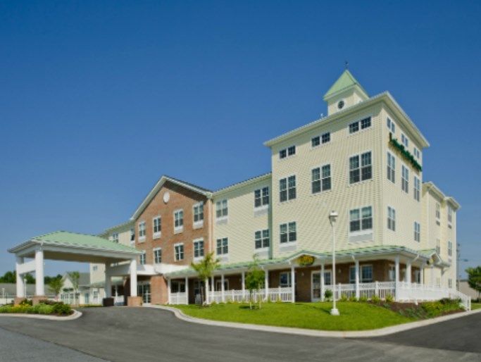 A modern healthcare facility with a multi-story building and a clear blue sky backdrop.