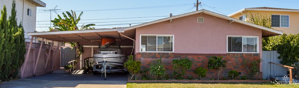 A suburban house with a boat parked under its carport.