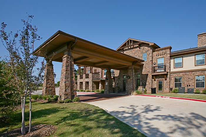 A stone building with a covered entrance and landscaped grounds.