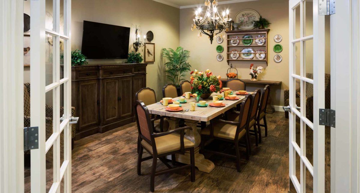 A cozy dining room with a set table, wooden furniture, and decorative elements.