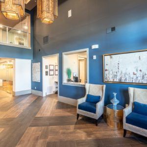 A modern lobby with blue walls, comfortable chairs, and stylish decor.