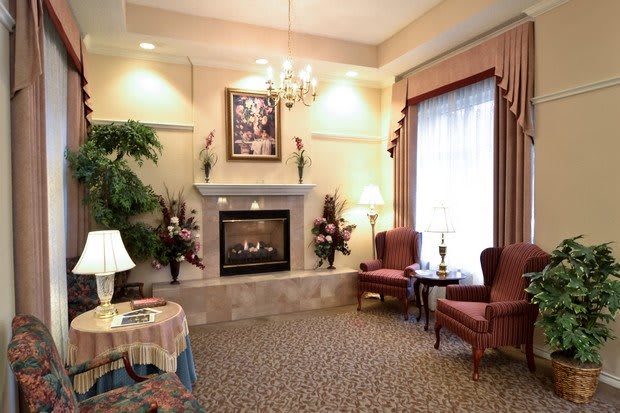 A cozy living room featuring a fireplace, two armchairs, and elegant decor.