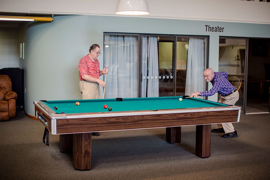 Two people playing billiards indoors on a pool table.