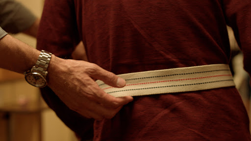 A close-up of a hand holding a measuring tape wrapped around the waist.