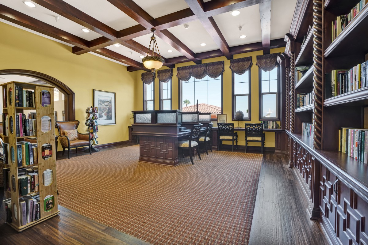 A spacious office with a wooden desk, bookshelves, and large windows.