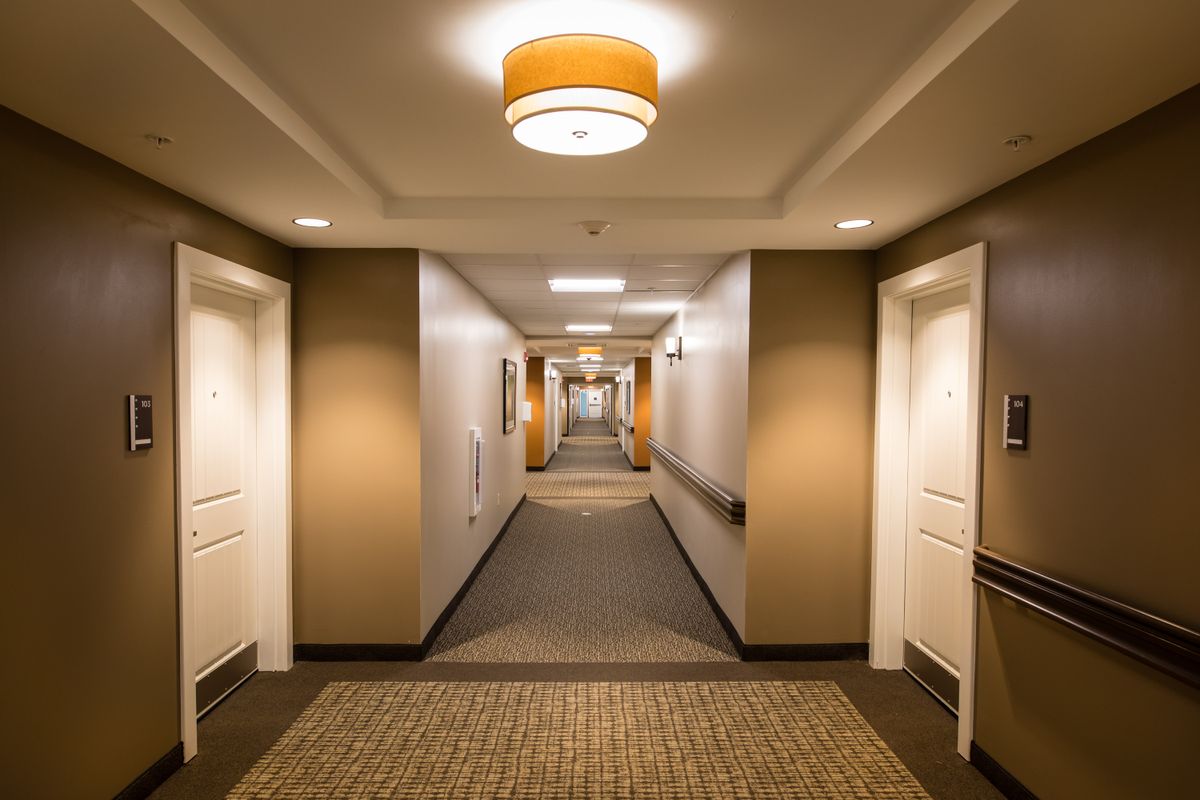 A well-lit hotel hallway with carpeted floors and multiple doors.
