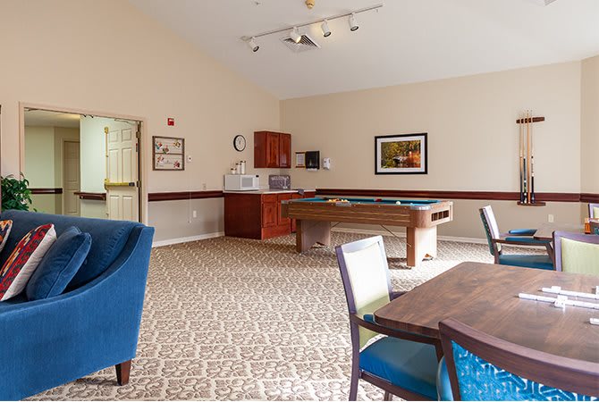 A game room featuring a pool table, seating area, and carpeted floor.