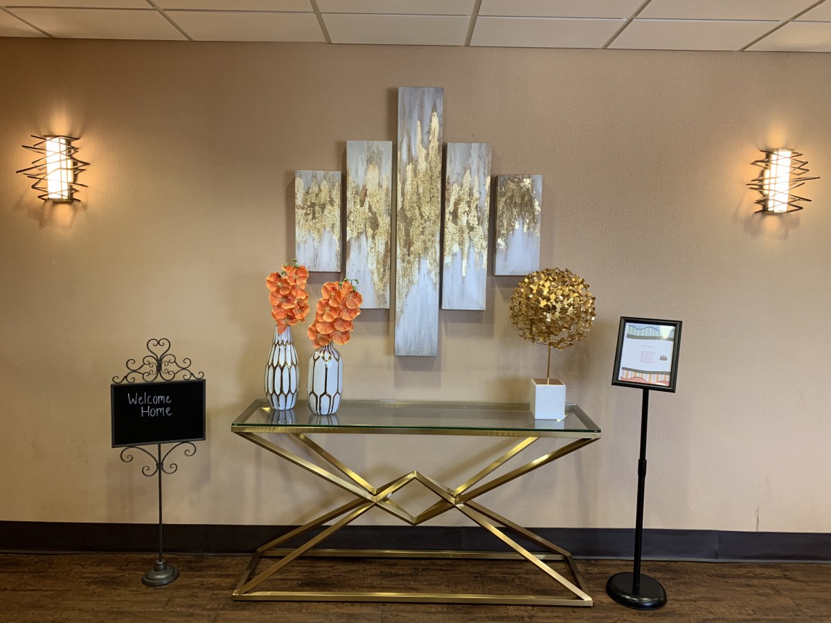 A modern lobby setup featuring a decorative console table with vibrant floral arrangements and abstract wall art.