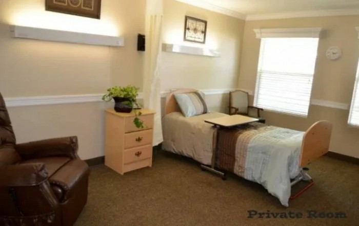 A cozy bedroom with a single bed, dresser, and chair, featuring soft lighting and a window.