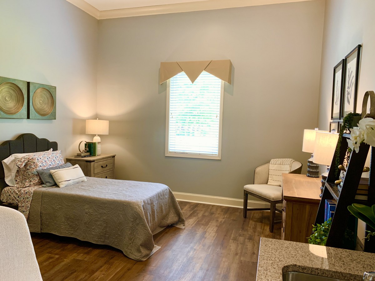 A cozy bedroom featuring a single bed, desk, and soft lighting.
