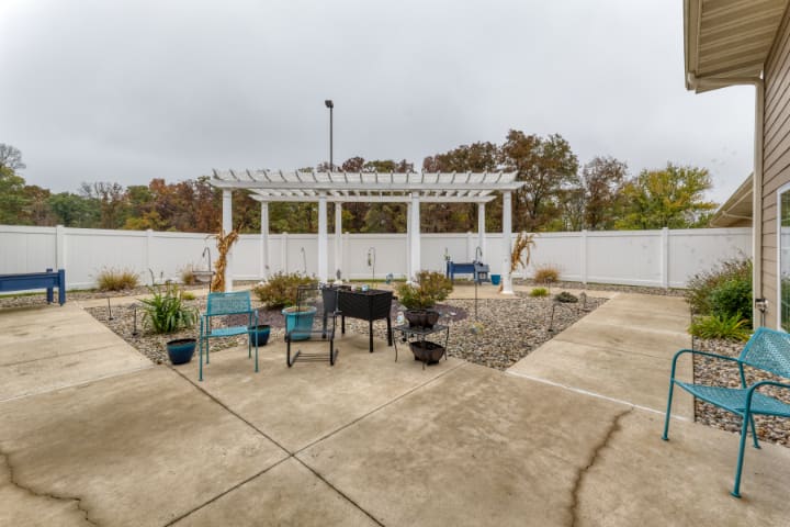 An outdoor patio area with a pergola, seating, and potted plants.