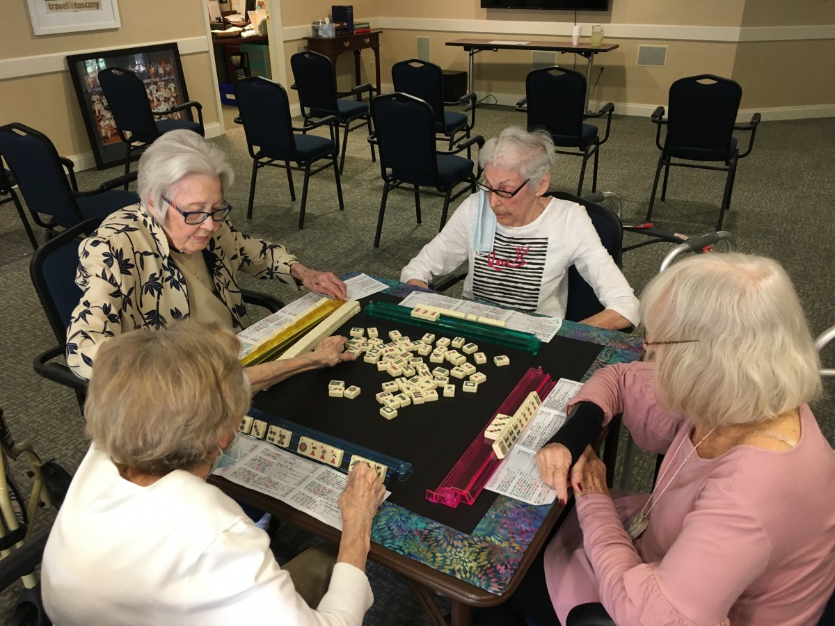 A group of seniors playing Mahjong together indoors.
