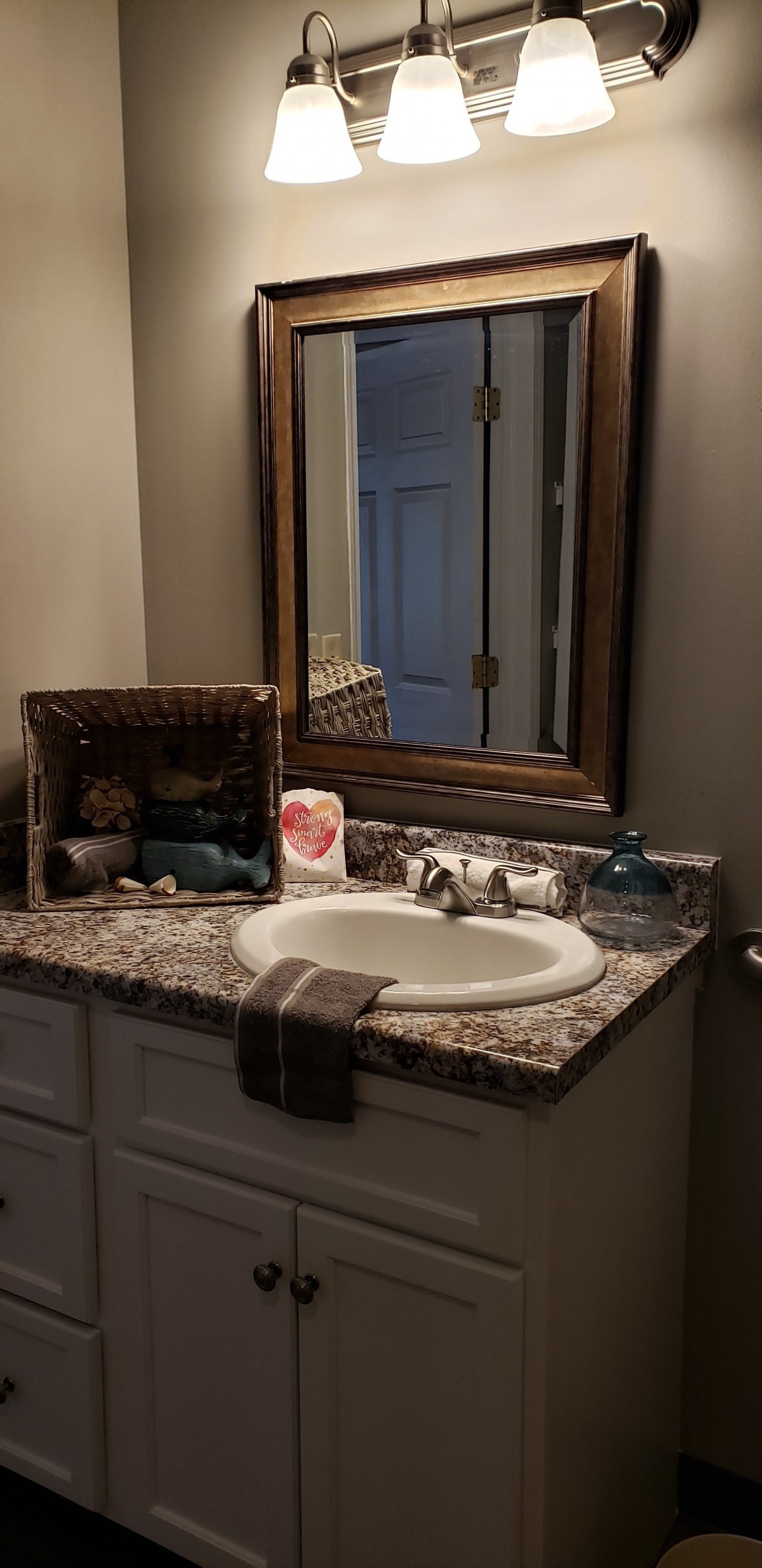 A neatly organized bathroom countertop with a sink, mirror, and decorative items.