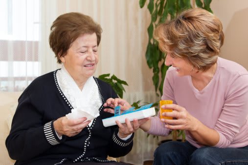 A caregiver assisting an elderly woman with her medication in a home setting.