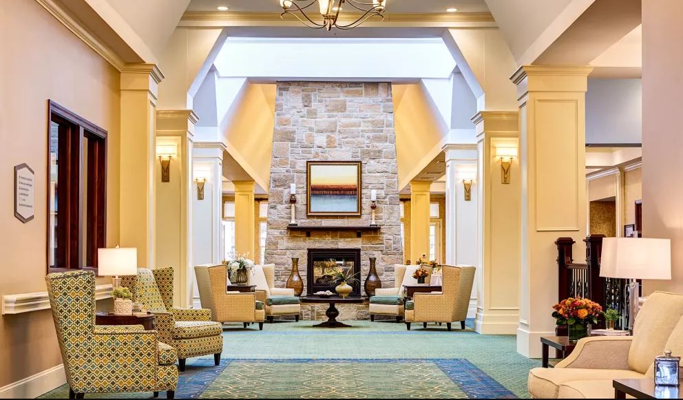 A cozy lounge with a central fireplace, surrounded by comfortable seating.