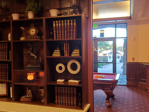 A cozy interior featuring a bookshelf filled with books and decorative items, leading to a room with a pool table.