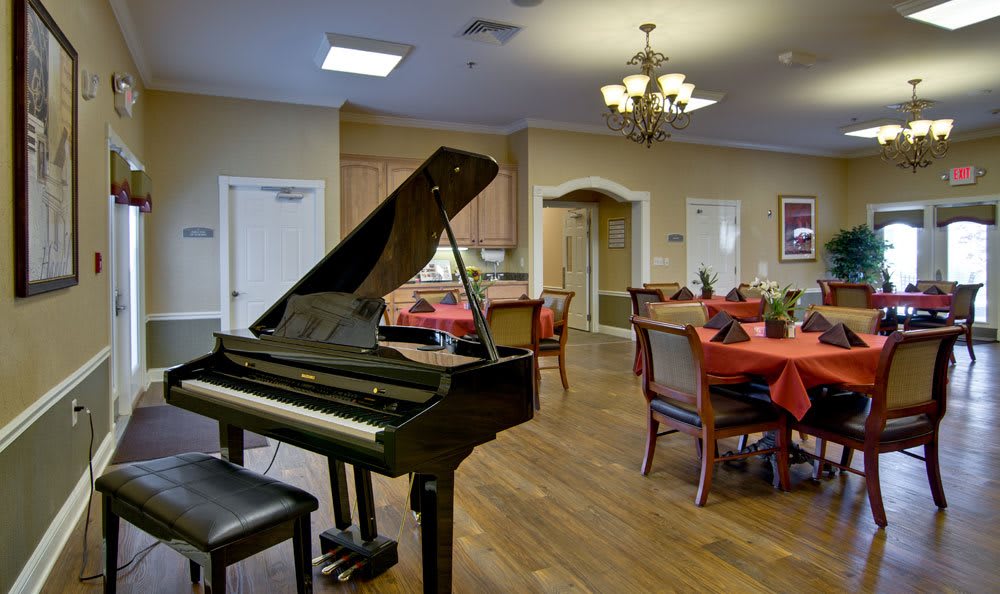 A dining area with a grand piano and elegantly set tables.