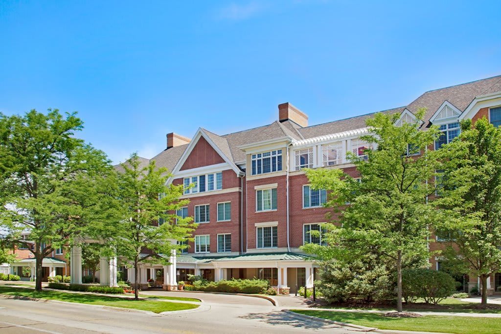 A large residential building with trees and a clear blue sky.