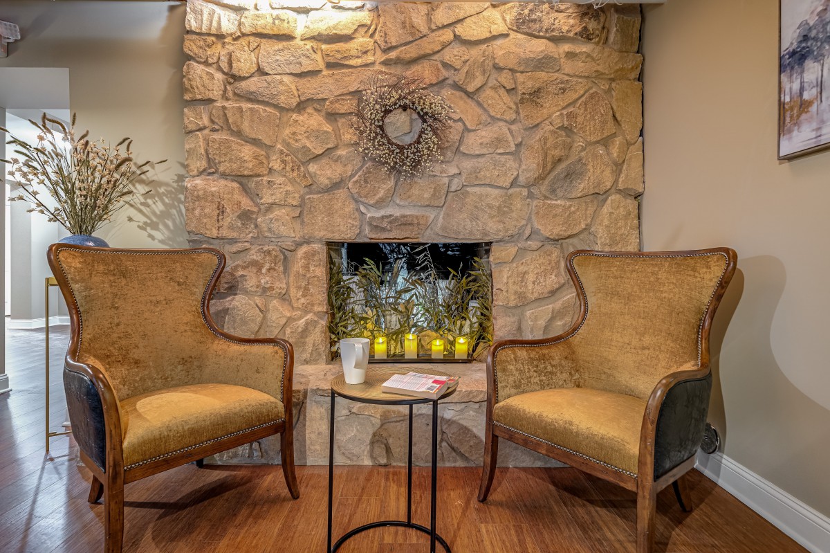 A cozy seating area with two armchairs beside a stone fireplace and a small round table.
