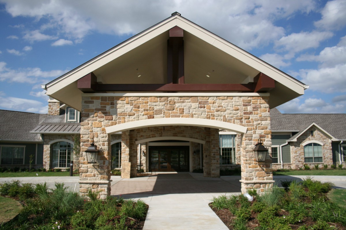 A residential building entrance with a stone facade and landscaped pathway.