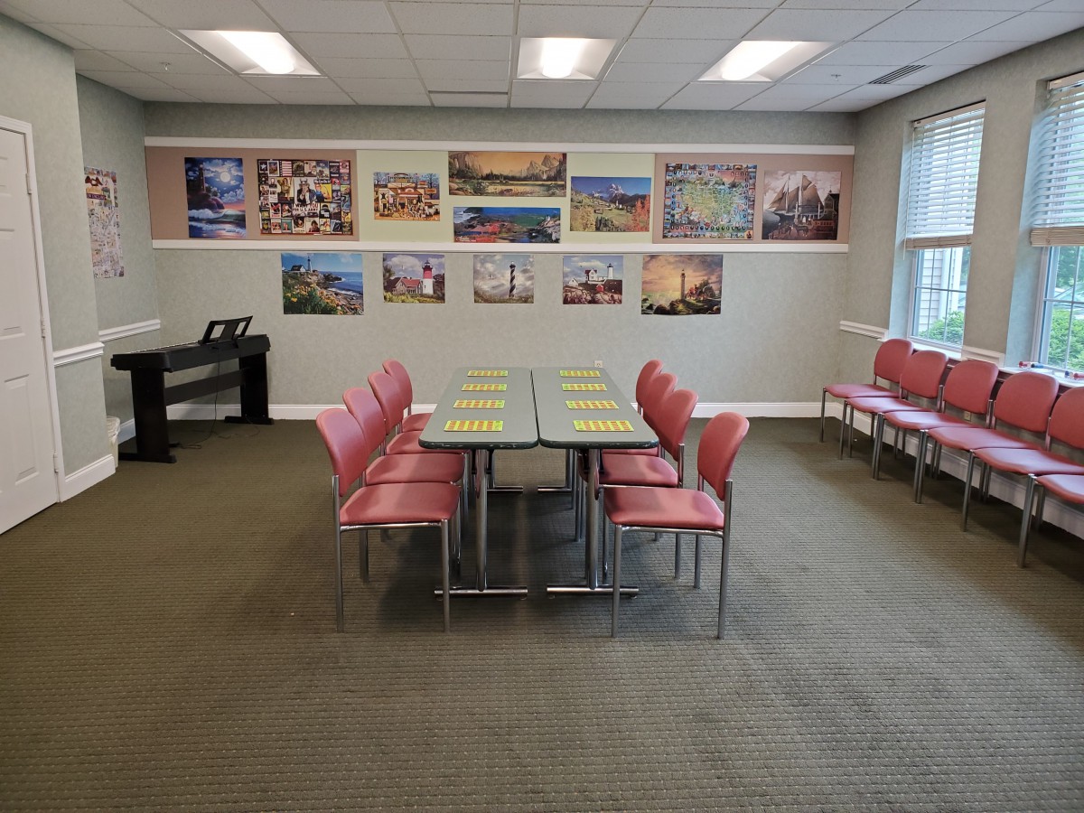 A well-lit conference room with a central table surrounded by red chairs and artwork displayed on the walls.