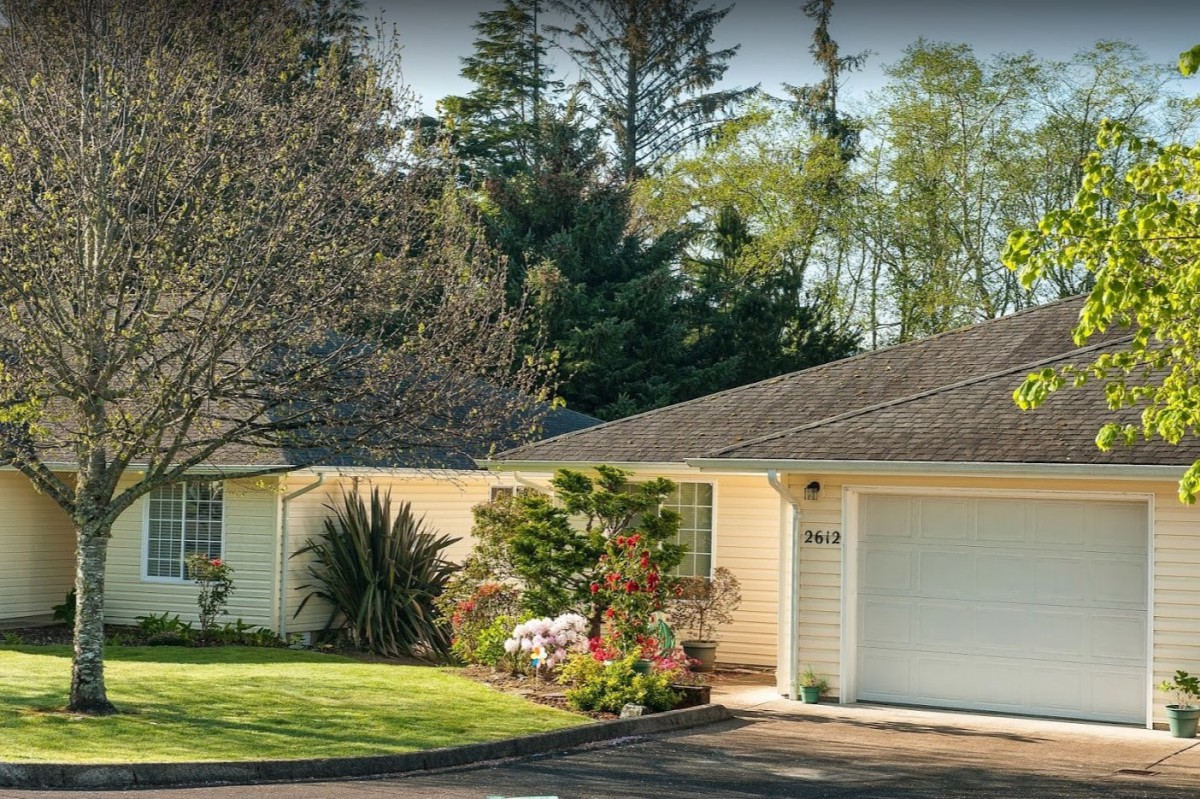 A suburban house with a neatly maintained front yard and surrounding trees.