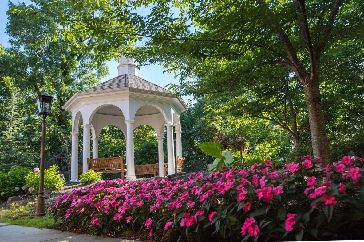 A picturesque gazebo surrounded by vibrant pink flowers in a lush garden.